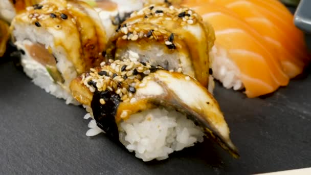 Sushi rolls in variety mix on black stone plate — Stock Video