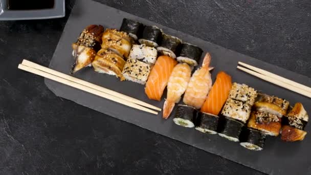 Variety mix of traditional sushi rolls on black stone plate — Stock Video