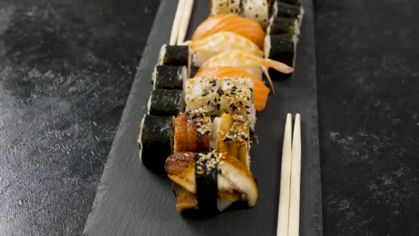 Rolos de sushi tradicional na placa de pedra preta — Vídeo de Stock
