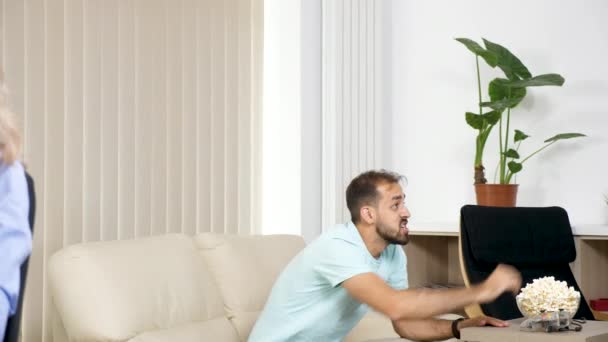 Rack fokus på från bullriga pojkvän medan wathcing Tv till sin flickvän som arbetar vid datorn i samma rum — Stockvideo