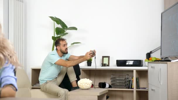 Lawaaierige vriendje speelt video spel terwijl freelancer vriendin thuis werkt — Stockvideo