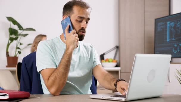 Homme parle au téléphone et les types sur l'ordinateur tandis que sa petite amie joue à un jeu vidéo dans le backgorund — Video