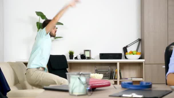 Homme regarde des jeux de football et fait du bruit tandis que son partenaire essaie de travailler sur l'ordinateur — Video