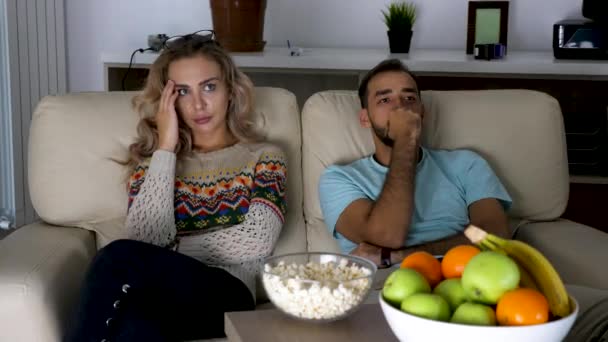 Couple watches a scary movie on the couch in living room — Stock Video