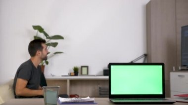 Bilgisayar yeşil mock-up ekran ve arka planda bulanık konsol video oyunları oynarken bir adam