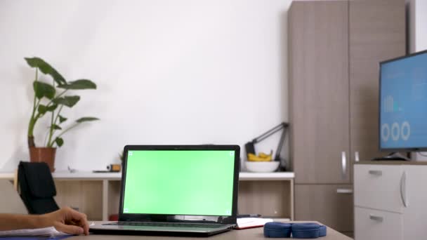 Человек за столом перед компьютером с зеленым экраном — стоковое видео