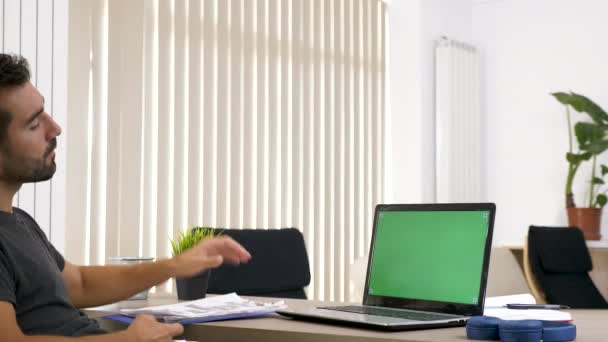 Hombre en la sala de estar mirando a la pantalla de la maqueta verde en el ordenador — Vídeo de stock