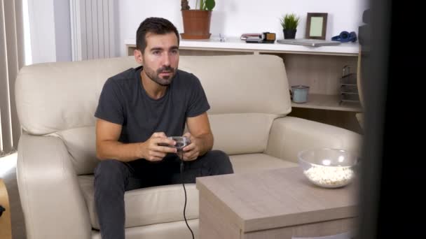 Дорослий чоловік грає в відеогру на консолі у вітальні — стокове відео
