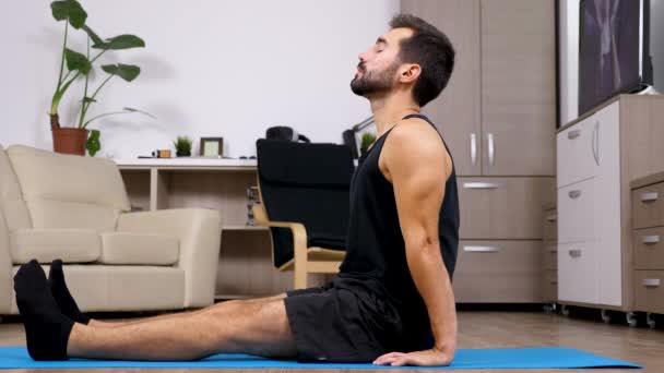 Homme relaxant dans différentes poses de yoga sur un tapis bleu — Video