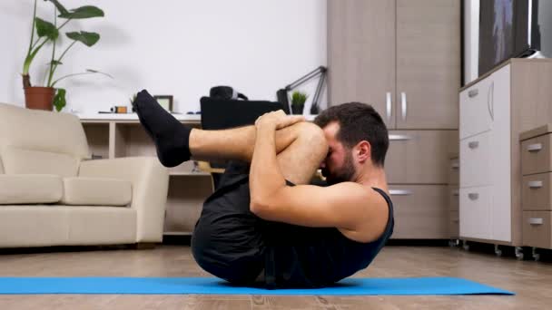 Ung passar mannen på golvet i sitt vardagsrum gör olika yogaställningarna — Stockvideo