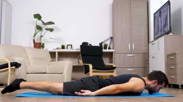 Onun oturma odasında bir mavi mat uygun erkek farklı yoga pozlar yapar — Stok video