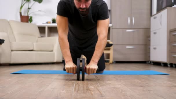 Ajuste hombre usando una rueda abdominales para ejercicios — Vídeo de stock