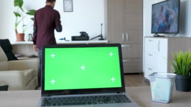 Moder dairede yeşil ekran mock-up ile bir dizüstü bilgisayar masaya oturur.