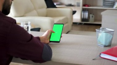 Bir smartphone yeşil ekran renk ile sahte kadar elinde tutan adam