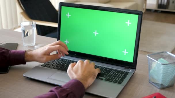 Draufsicht eines Mannes in seinem Haus, der an einem Laptop mit einer Chroma-Attrappe für den grünen Bildschirm arbeitet — Stockvideo