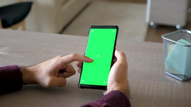 Erkek el Smartphone ile yeşil ekran renk kaydırma masasında alay