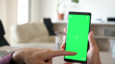Modern bir akıllı telefon ile yeşil ekran renk üzerine sahte kullanan adam, yakın çekim