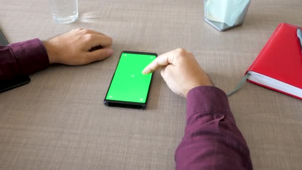 Smartphone with green screen chroma mock up on the table and male hands working on it — Stock Video