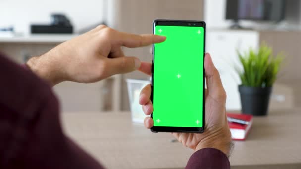 Hombre desplazándose a mano hacia abajo en un teléfono inteligente con croma pantalla verde se burlan de — Vídeos de Stock