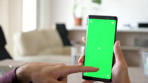 Primo piano dell'uomo con uno smartphone moderno con schermo verde cromato modello su di esso — Video Stock