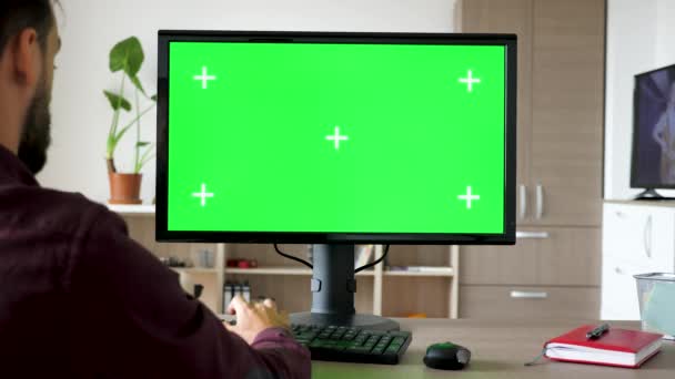 Oldalnézetből ember ül a számítógép előtt, nagy zöld képernyő modell chroma gépelés-on billentyűzet