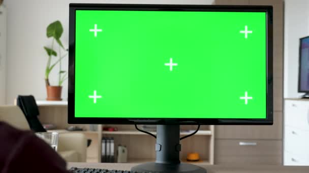 Неузнаваемый человек смотрит на современный персональный компьютер с большим зеленым экраном хрома макет — стоковое видео
