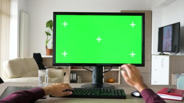 Вид от первого лица - руки человека, печатающие на клавиатуре компьютера с большим зеленым экраном хрома макет — стоковое видео