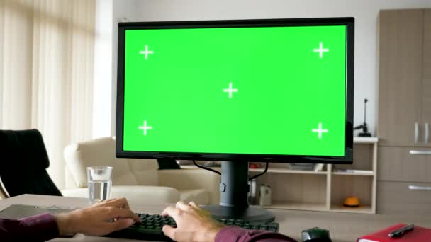 Widok pierwszej osoby - ręce człowieka, wpisując na klawiaturze komputera z duży zielony ekran chroma makiety — Wideo stockowe