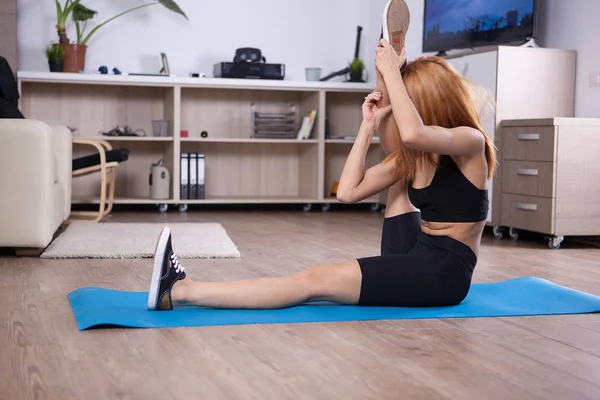 Ragazza bionda allungando il tendine del ginocchio durante il suo tempo di yoga . — Foto Stock