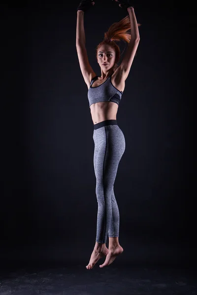 Fitness menina fazendo salto pose enquanto ela é em um estúdio photoshoot . — Fotografia de Stock