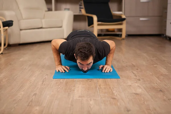 Bebaarde man doet push ups op de vloer van zijn huis. — Stockfoto