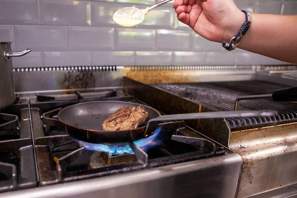 Chef tempero carne na panela enquanto cozinha — Fotografia de Stock