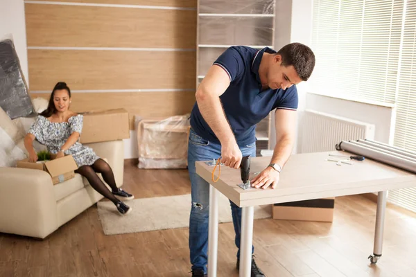 El hombre utiliza herramientas para ensamblar muebles en una casa nueva . — Foto de Stock