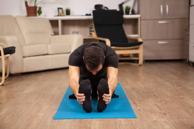 Paschimottanasana yoga poz yapıyor katta oturan genç adam