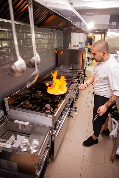 Chef cozinhar com chama em uma frigideira em um fogão de cozinha. — Fotografia de Stock