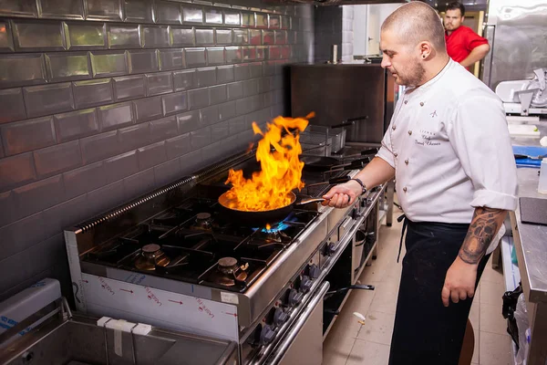 Cozinheiro masculino fazendo marisco inflamatório no fogão na cozinha do restaurante — Fotografia de Stock