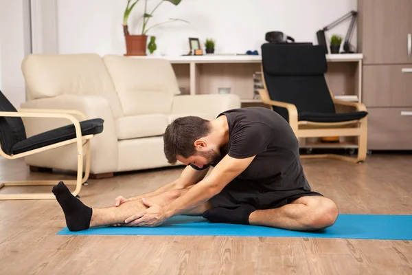 Jonge man praktizerende yoga in zijn woonkamer — Stockfoto