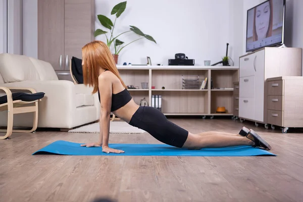 Ragazza bionda che fa cobra yoga posa nella sua casa — Foto Stock