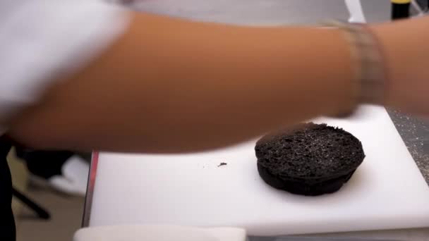 Cook hands seasoning and prepraring a black burger bun — Stock Video