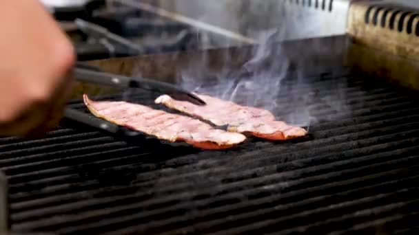 Gotować ręce turnin dwa kawałki boczku wędzonego na grill — Wideo stockowe