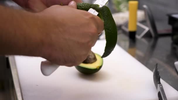 Крупным планом руки повара чистят авокадо — стоковое видео