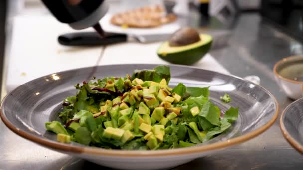 Männliche Hände gießen Sauce ein und würzen Avocadosalat — Stockvideo