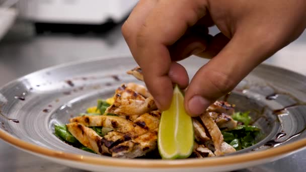 Cook handen plaatsen van een stuk van kalk op avocado salade met gegrilde vlees — Stockvideo