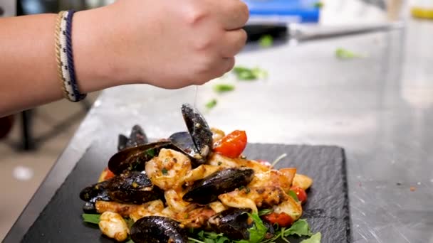 Шеф-повар выжимает лимон над тарелкой с вареными морепродуктами — стоковое видео