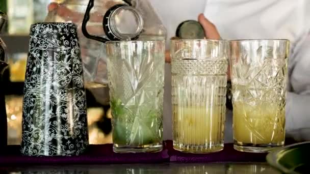 Barman stromende water in cocktails — Stockvideo