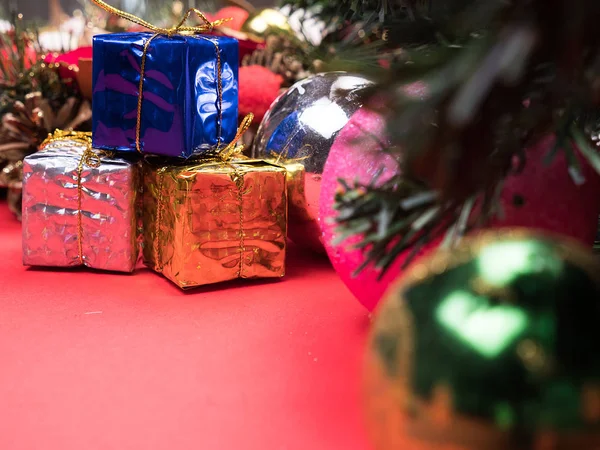 Рождественские подарочные коробки в разных цветах под елкой на красном фоне — стоковое фото