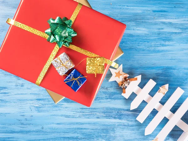 Большая красная коробка подарков на Рождество с меньшими коробками на голубом винтажном деревянном фоне — стоковое фото