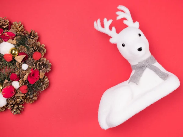 Hermosa corona de Navidad con juguete de reno blanco sobre fondo rojo — Foto de Stock