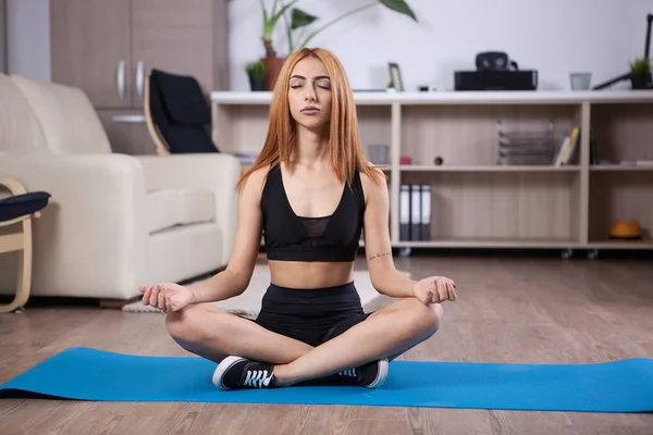 Attraente ragazza seduta in posizione loto yoga nella sua casa — Foto Stock