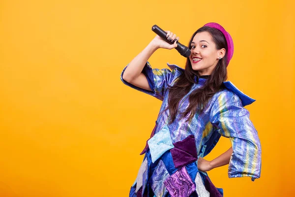 Hermosa joven vistiendo ropa funky y cantando micrófono . — Foto de Stock